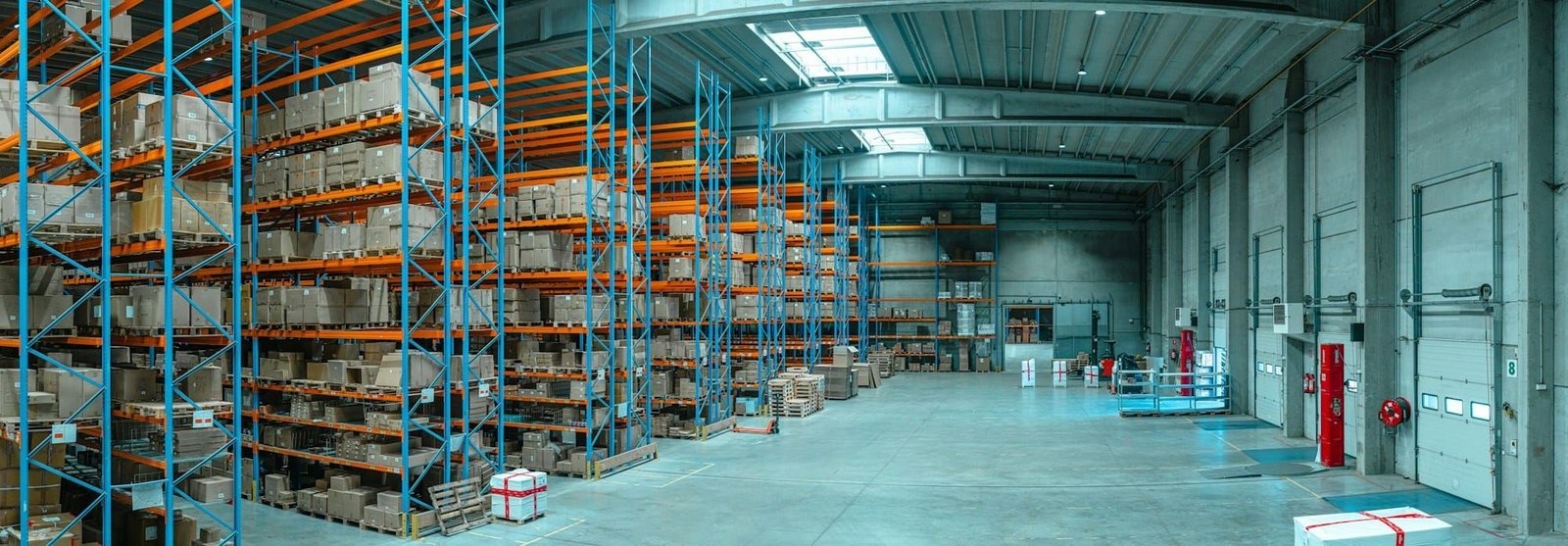 Tall blue metal shelving units filled with cardboard boxes in a large, organised warehouse