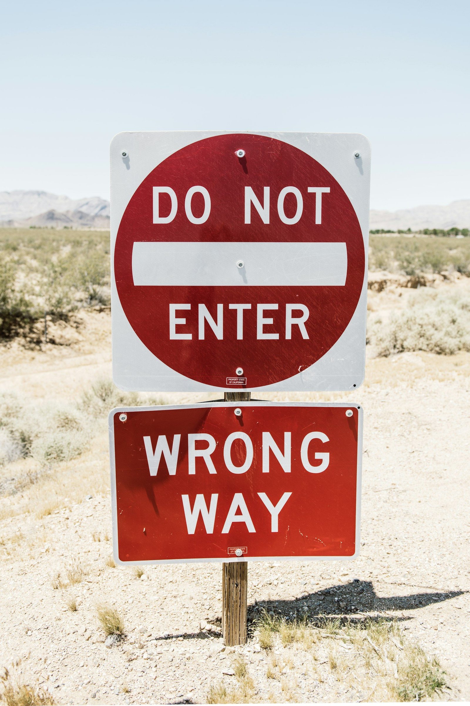 Red and white "Do not enter" and "Wrong way" road signs in a dry landscape
