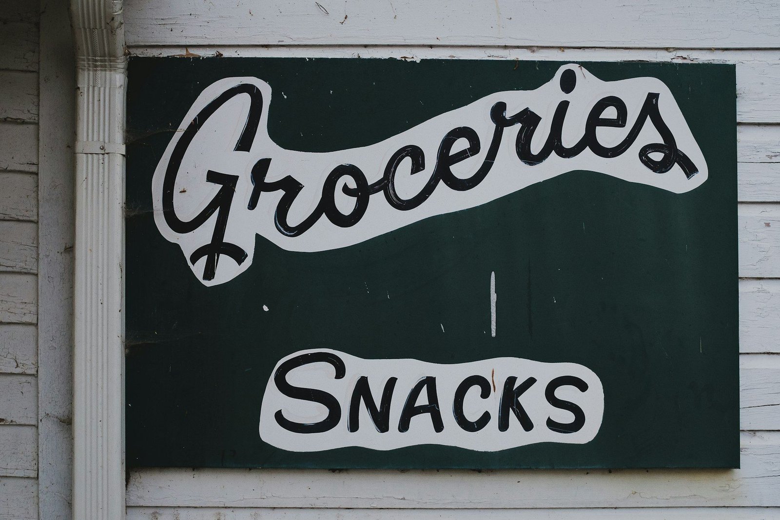 A painted "Groceries" and "Snacks" shop sign on a wooden wall
