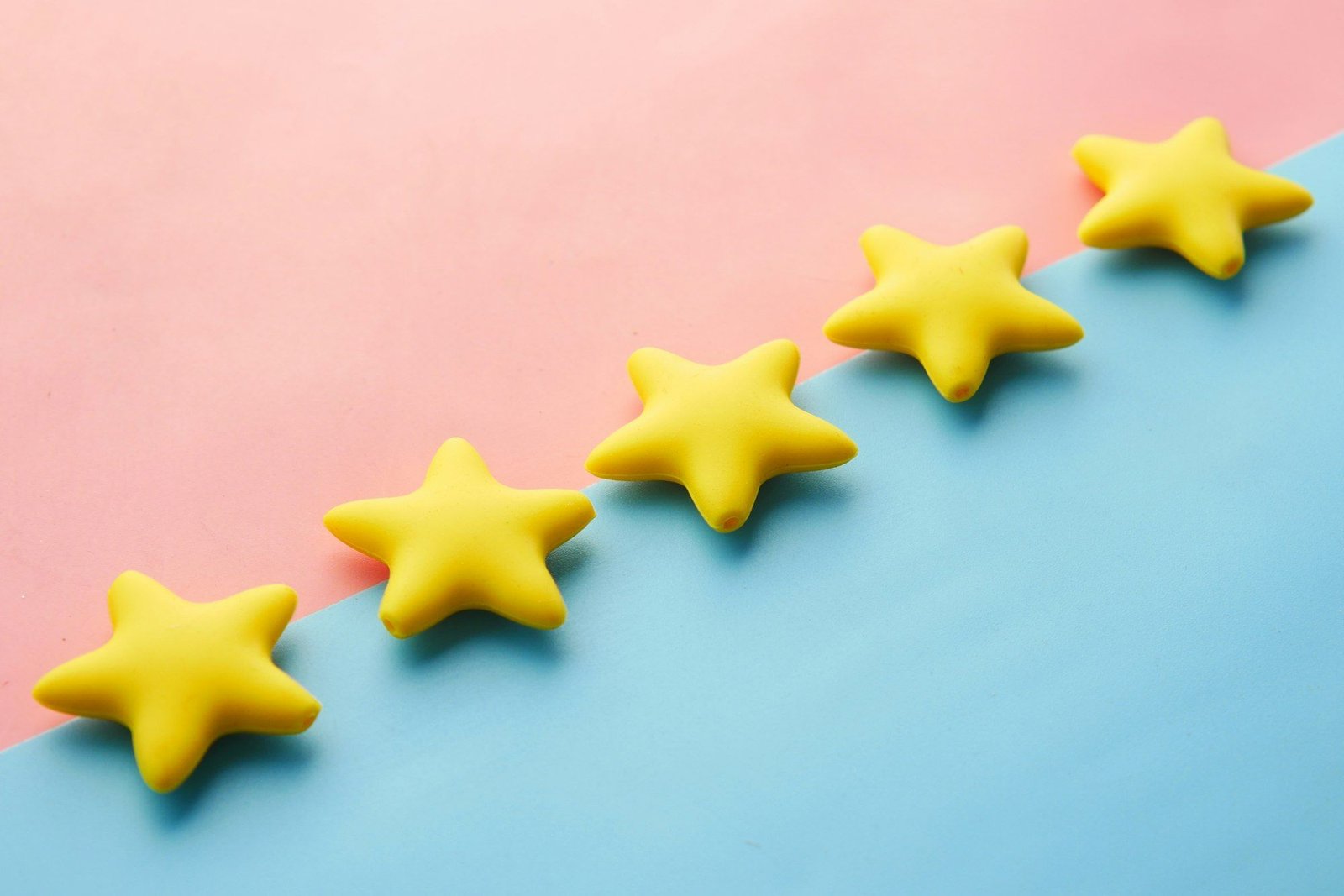 Five yellow star shapes lined up diagonally on a pink and blue background