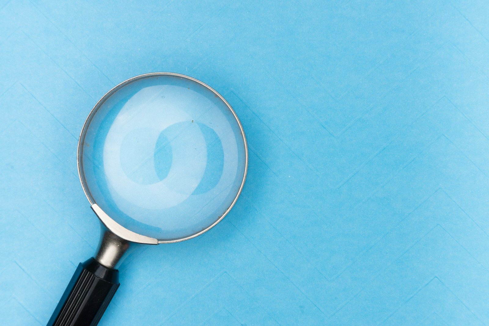 A magnifying glass lying on a plain light blue background