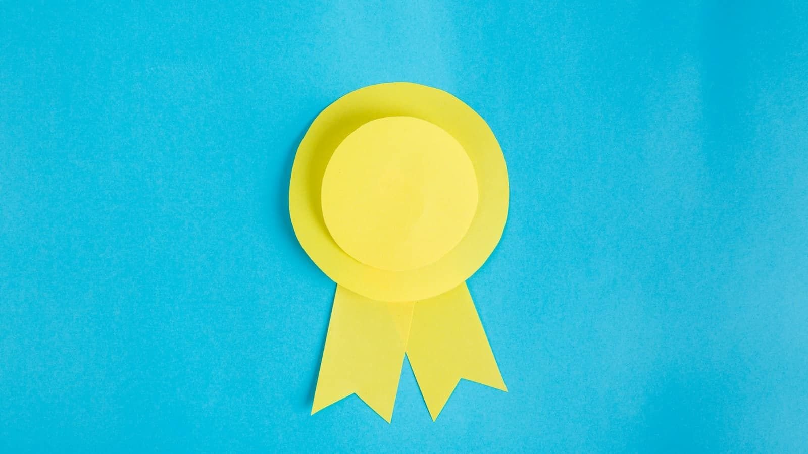 A yellow paper award rosette on a bright blue background