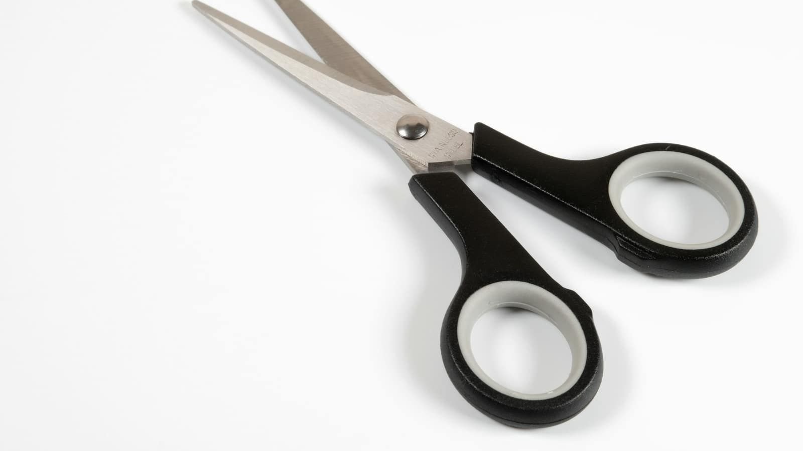 A pair of black-handled scissors lying on a plain white surface