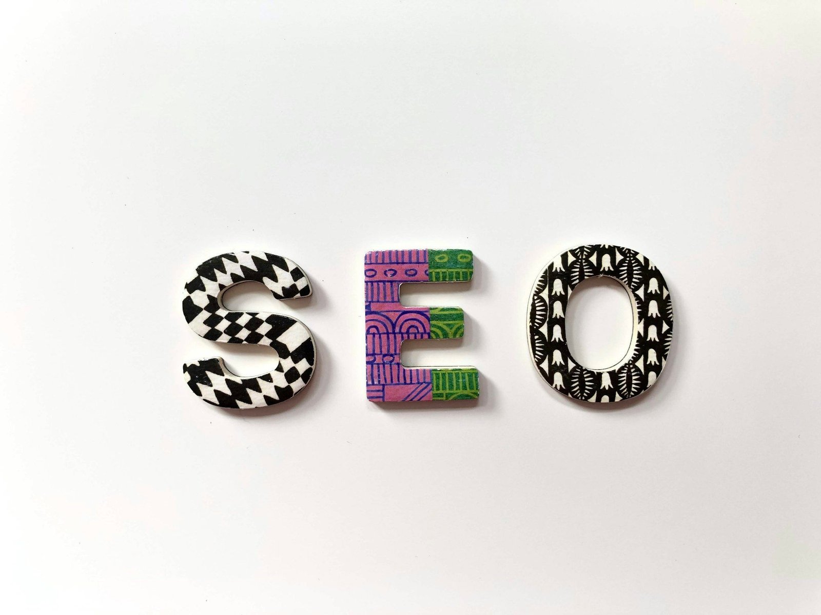 The letters S, E and O in patterned black, white and purple designs on a white background