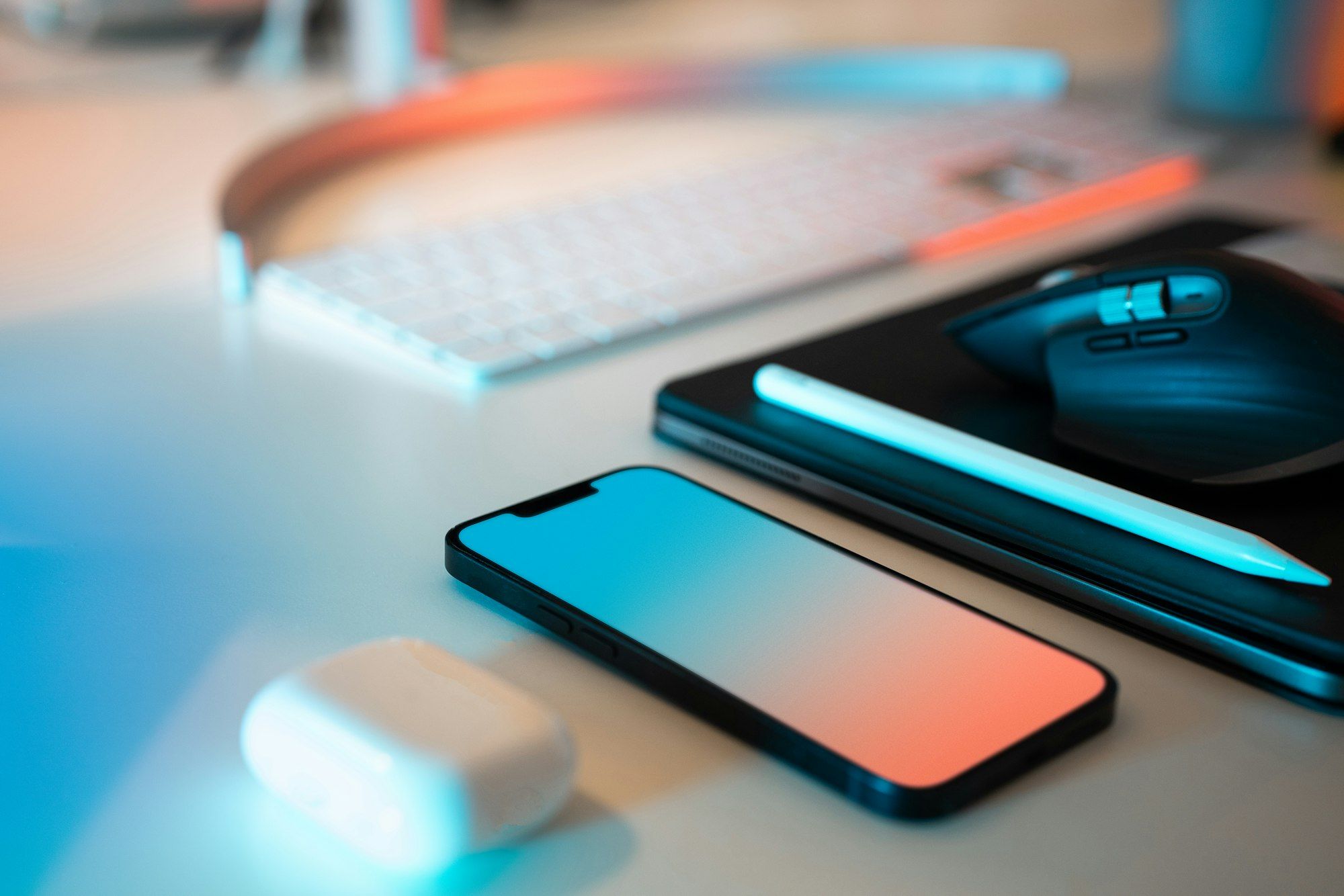 A smartphone lying on a desk next to a keyboard, a mouse and a tablet